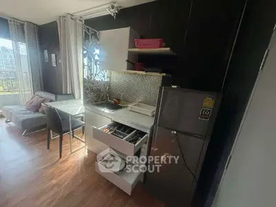 Modern compact kitchen with open layout and cozy living area in a stylish apartment.