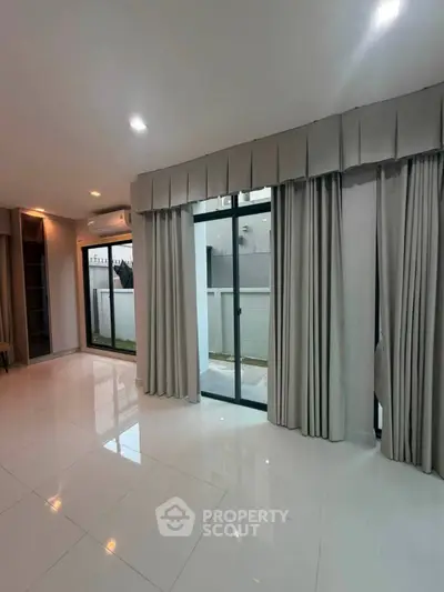 Spacious modern living room with large windows and elegant curtains, perfect for natural light and stylish living.