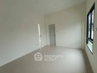 Spacious empty room with large window and tiled floor, ideal for customization.