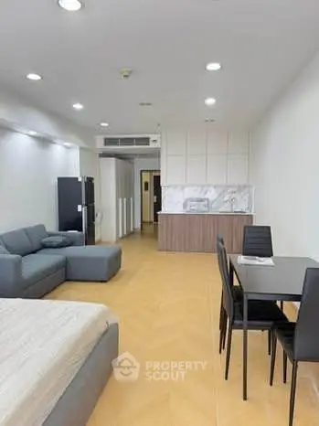 Modern open-plan living room with sleek furniture and stylish kitchen area.