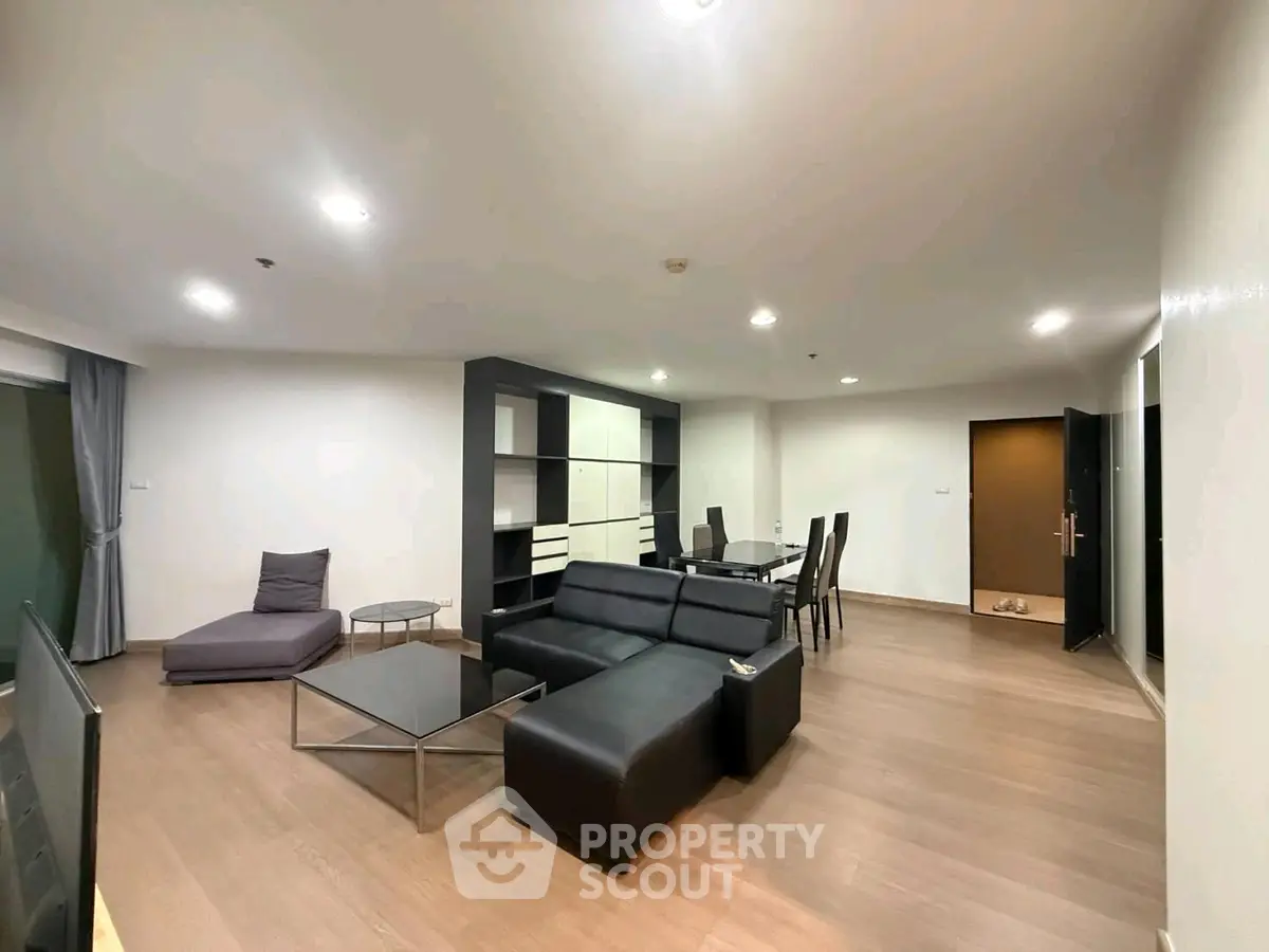 Spacious modern living room with sleek black furniture and open layout in a contemporary apartment.