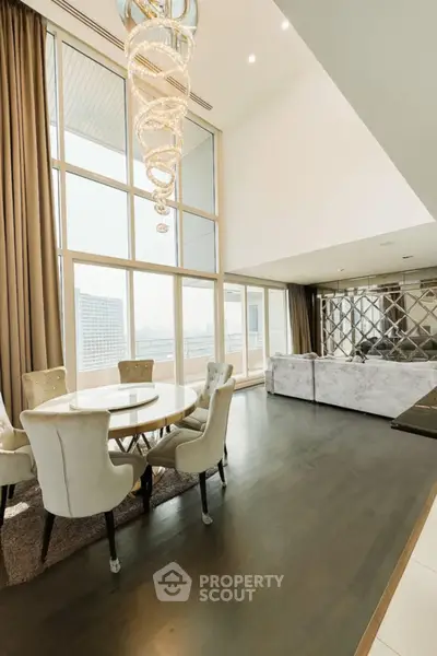 Luxurious high-ceiling living room with elegant chandelier and panoramic city view.