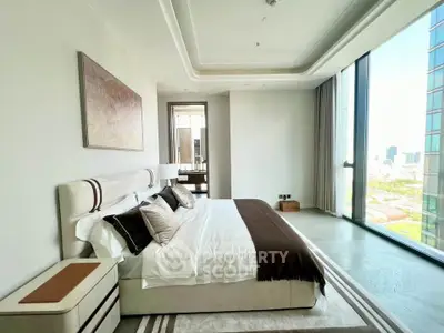 Luxurious bedroom with floor-to-ceiling windows offering stunning city views, elegant decor, and modern furnishings.