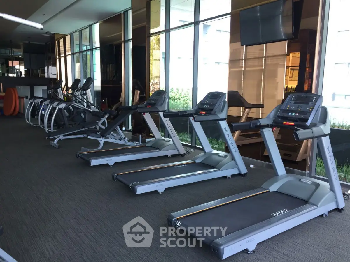 Modern gym with treadmills and exercise equipment in a luxury residential building.