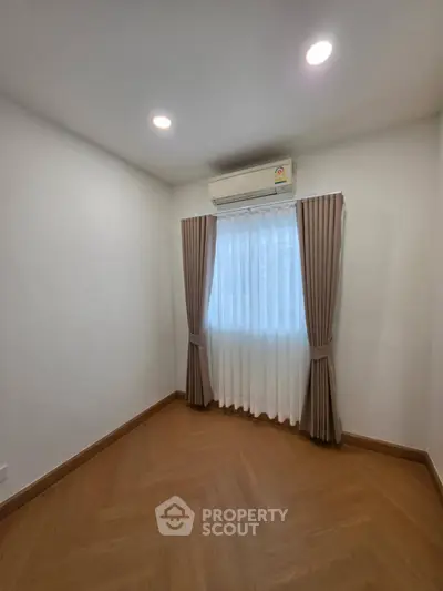 Cozy small room with wooden flooring and air conditioning, perfect for a study or compact bedroom.