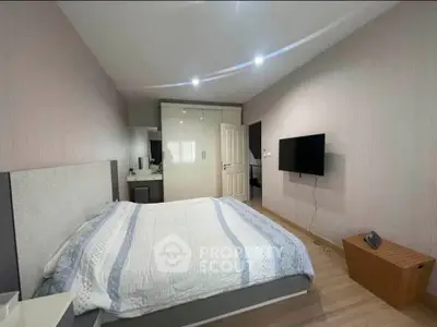 Modern bedroom with stylish decor and wall-mounted TV, featuring a cozy bed and ample storage space.