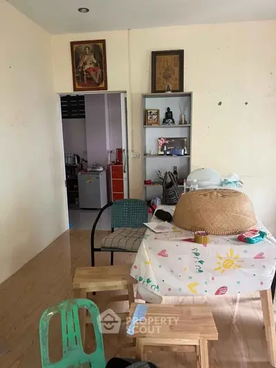 Cozy living area with eclectic decor and wooden flooring, adjacent to a compact kitchen.