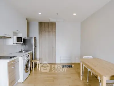 Modern kitchen with washing machine and dining area in open layout apartment.