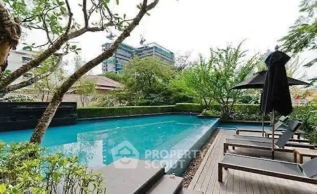 Luxurious outdoor pool area with sun loungers and lush greenery in a modern urban setting.