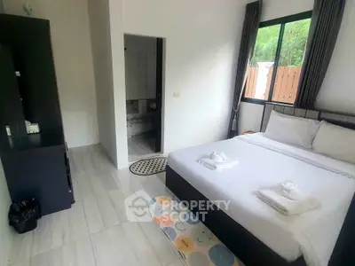 Cozy bedroom with modern decor and large window offering natural light