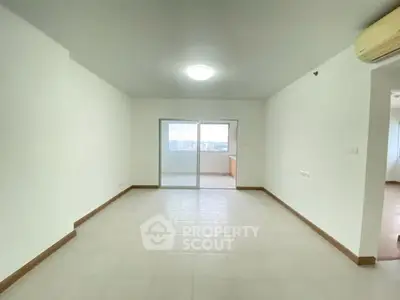 Spacious empty living room with large window and balcony access