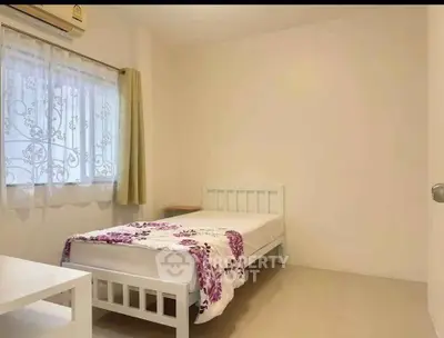 Cozy minimalist bedroom with single bed and floral bedding in bright apartment.