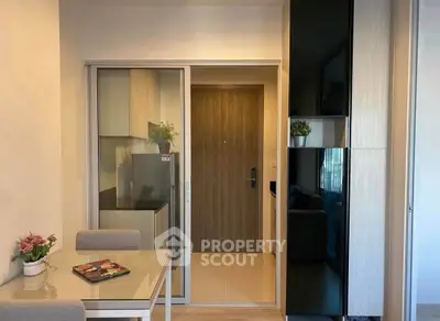 Modern apartment entrance with sleek kitchen and dining area, featuring stylish decor and efficient use of space.