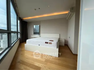 Spacious bedroom with large windows offering stunning city views and modern furnishings.