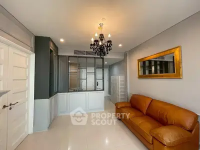 Elegant living room with leather sofa and chandelier, featuring a modern open layout and stylish decor.