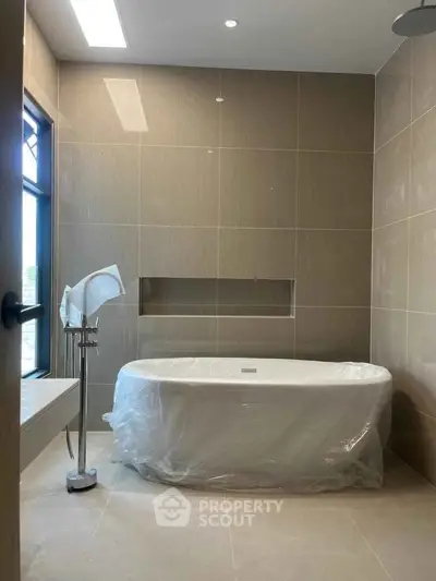 Luxurious modern bathroom with elegant freestanding bathtub and sleek tile design.