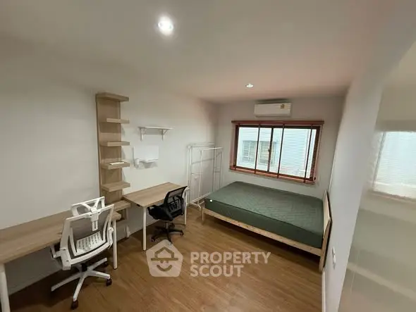 Modern bedroom with study area, featuring wooden flooring and natural light.