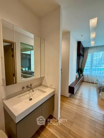 Modern bedroom with ensuite bathroom featuring sleek vanity and large window view.