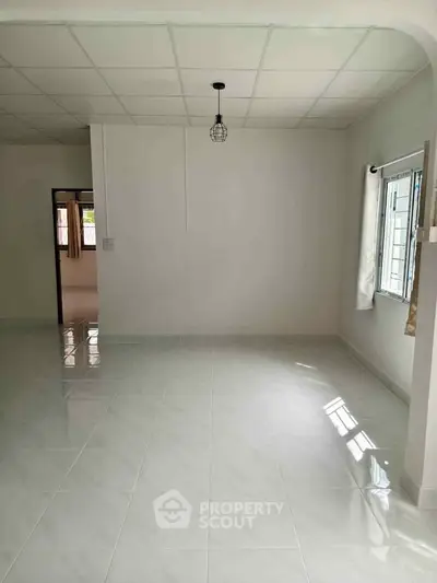 Spacious empty room with tiled flooring and natural light, ideal for customization.
