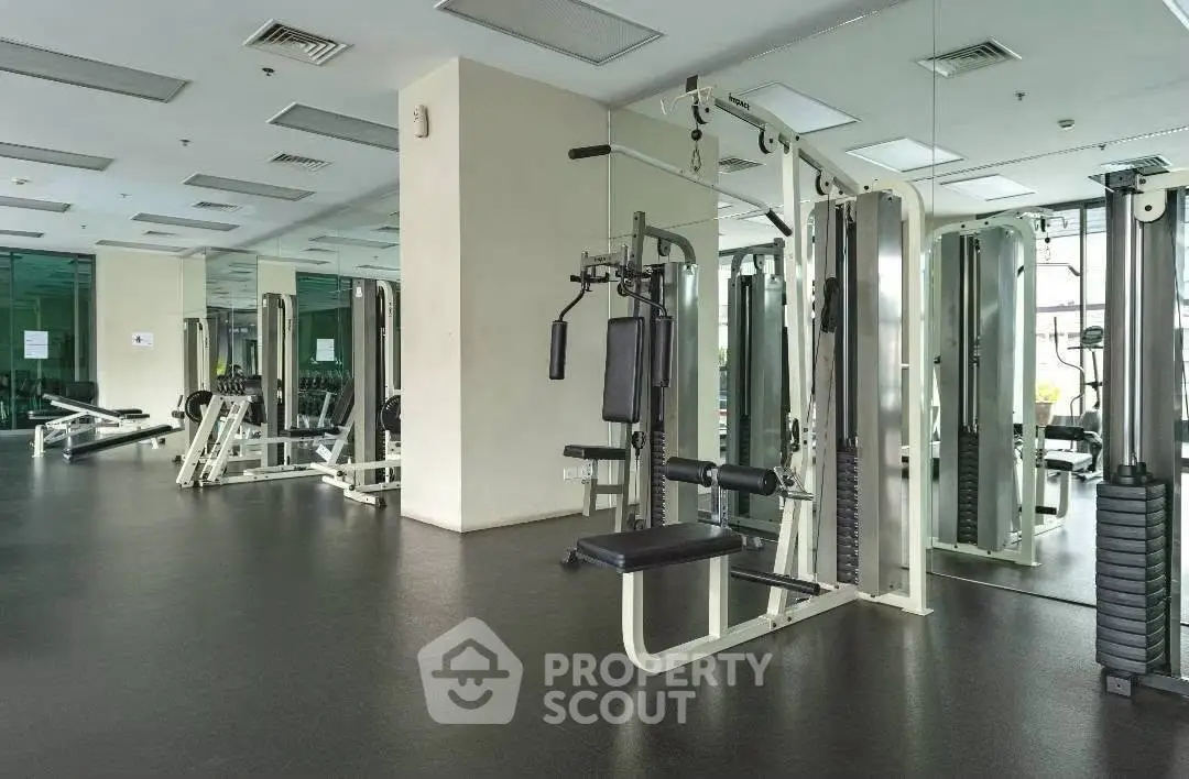 Spacious modern gym with state-of-the-art fitness equipment and mirrored walls in a luxury residential building.