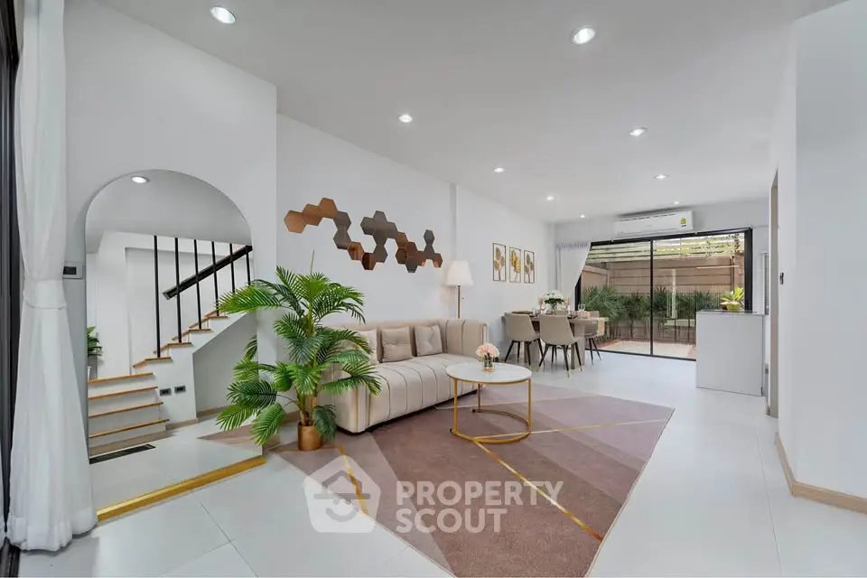 Modern living room with stylish decor and open layout, featuring a cozy sofa and elegant staircase.