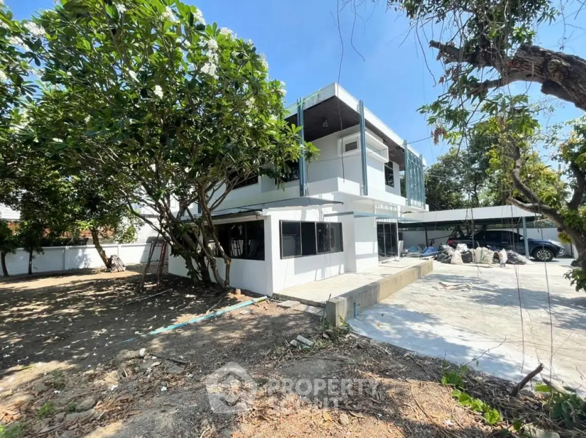 Modern two-story house with large windows and spacious yard under clear blue sky.