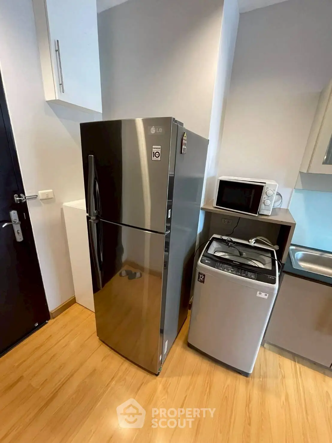 Modern kitchen with stainless steel fridge and washing machine in compact layout