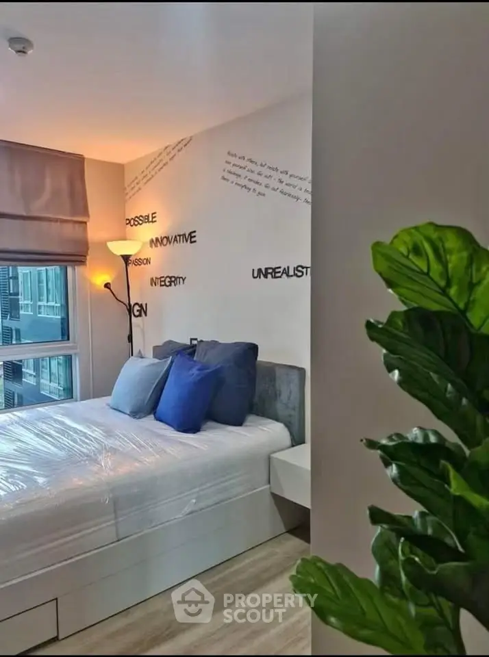 Modern bedroom with stylish decor and large window offering city views, perfect for urban living.