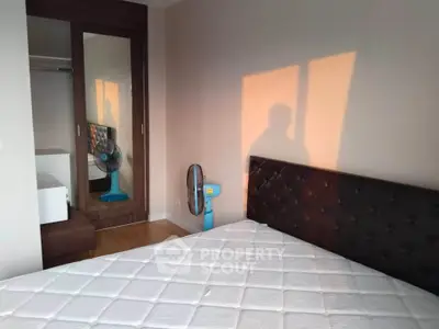 Cozy bedroom with mirrored closet and natural light, perfect for relaxation.