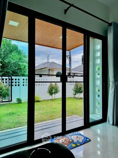 Spacious living room with large glass doors opening to a lush garden view, perfect for relaxation.