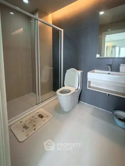 Modern bathroom with sleek design, featuring a glass shower enclosure and contemporary fixtures.