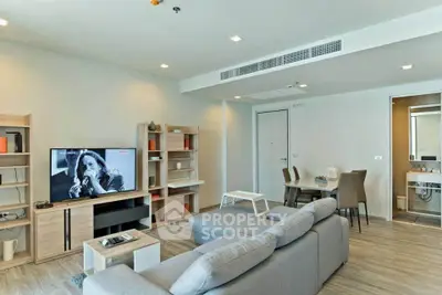 Modern living room with stylish furniture and open layout, featuring a cozy gray sofa and a large flat-screen TV.