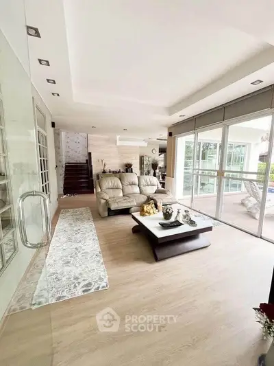 Spacious modern living room with elegant decor and large windows opening to a balcony.