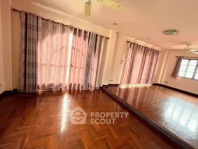 Spacious living room with elegant wooden flooring and large windows for natural light.