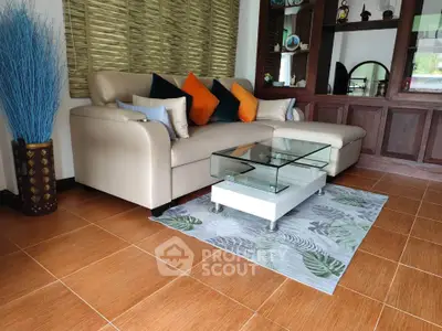 Stylish living room with modern beige sofa and glass coffee table on a decorative rug.