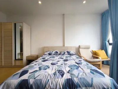 Spacious bedroom with modern decor and natural light, featuring a cozy bed and stylish chair.