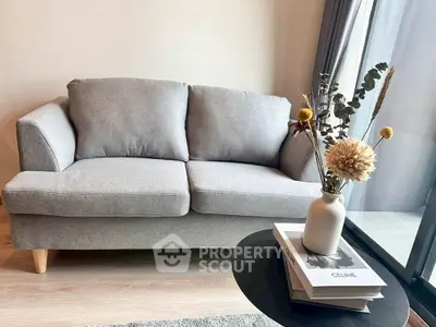 Stylish living room with cozy gray sofa and elegant decor near large window.