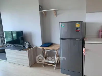 Modern living room with TV and fridge, minimalist design, bright natural light.