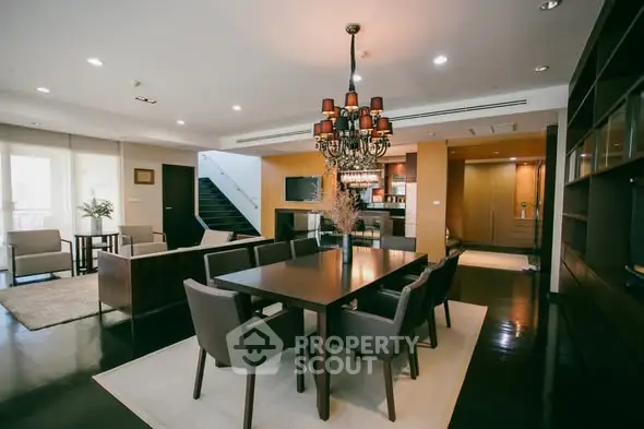 Luxurious open-plan living and dining area with elegant chandelier and modern furnishings.