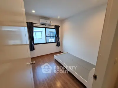Minimalist bedroom with wooden flooring and air conditioning