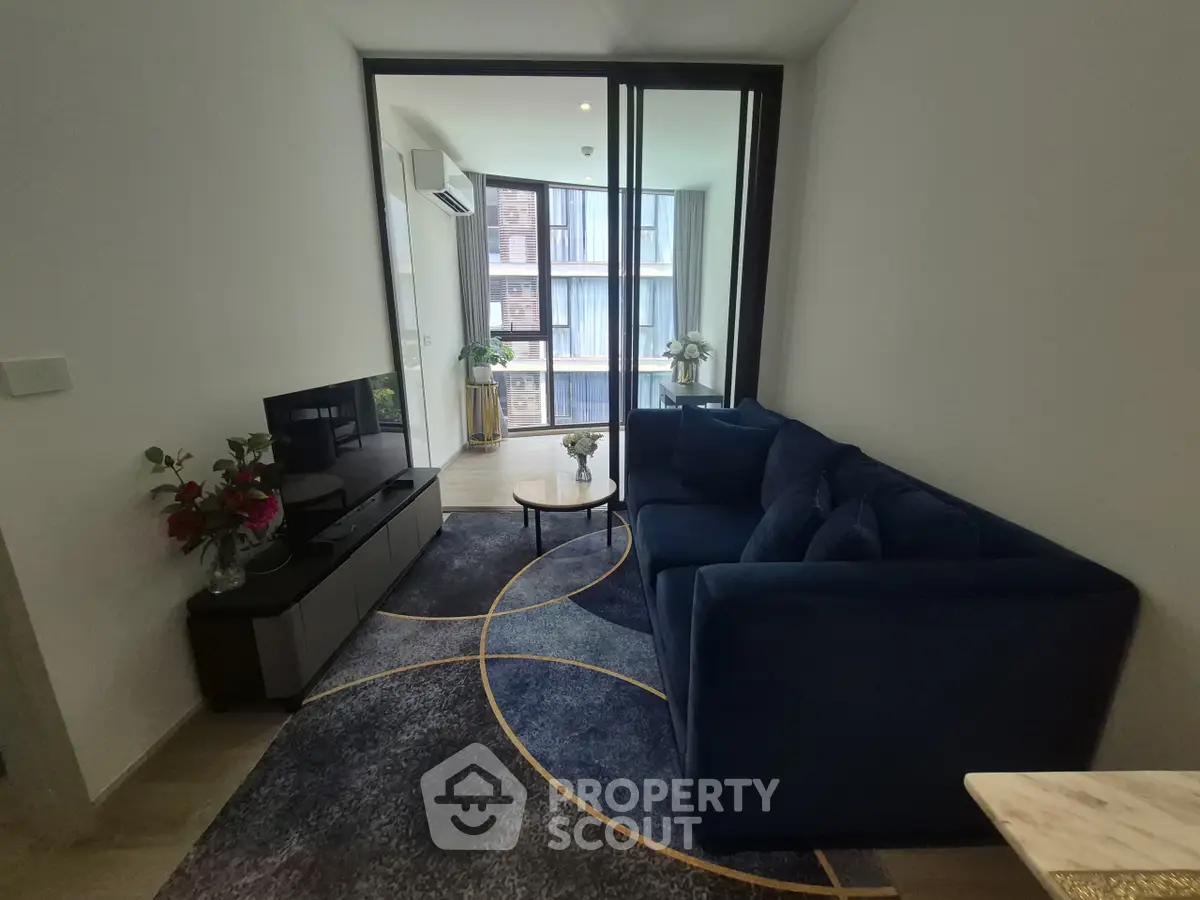 Modern living room with stylish blue sofa and large windows offering city views.