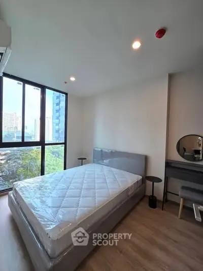 Modern bedroom with large window and city view, featuring a comfortable bed and stylish decor.