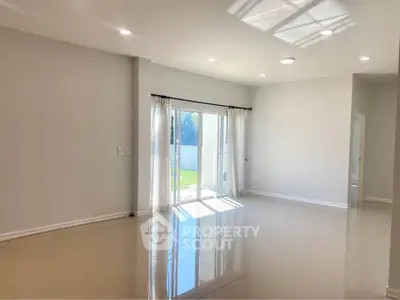Spacious empty living room with glossy floors and large window for natural light.