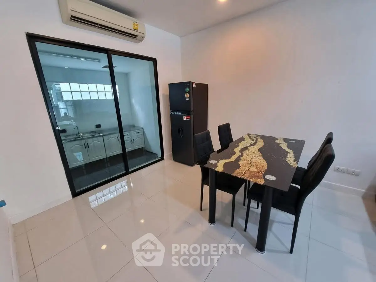 Modern dining area with glass partition and sleek kitchen view