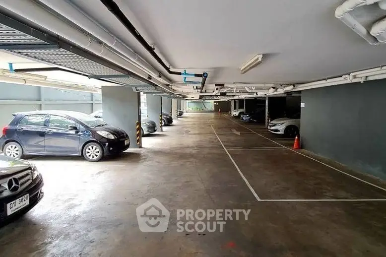 Spacious indoor parking area with multiple cars and ample lighting, ideal for secure vehicle storage.
