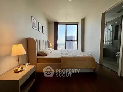 Modern bedroom with city view, featuring elegant decor and en-suite bathroom in a high-rise apartment.