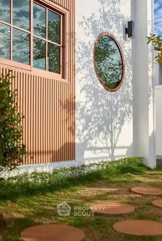 Charming modern exterior with round window and stepping stones in lush garden.