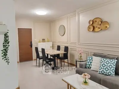 Elegant living room with modern decor and dining area, featuring stylish wall art and cozy seating.