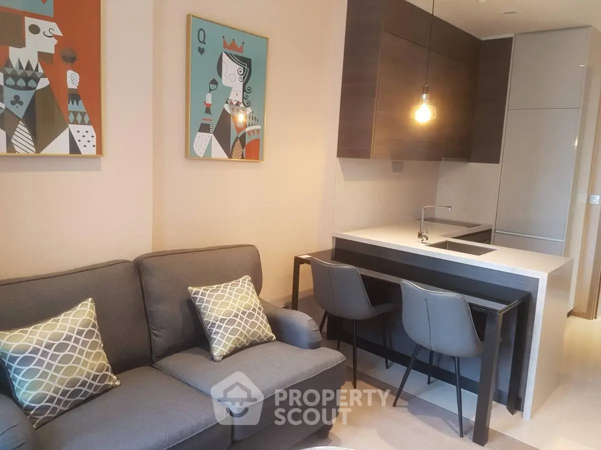 Modern open-layout kitchen and cozy living room with stylish decor and pendant lighting.