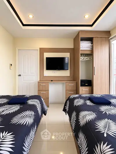 Modern bedroom with twin beds, built-in wardrobe, and wall-mounted TV in a stylish apartment.